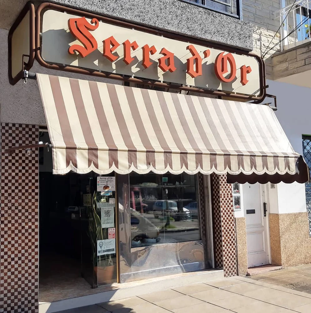 Frente del local Serra d’Or con su cartel y toldo a rayas