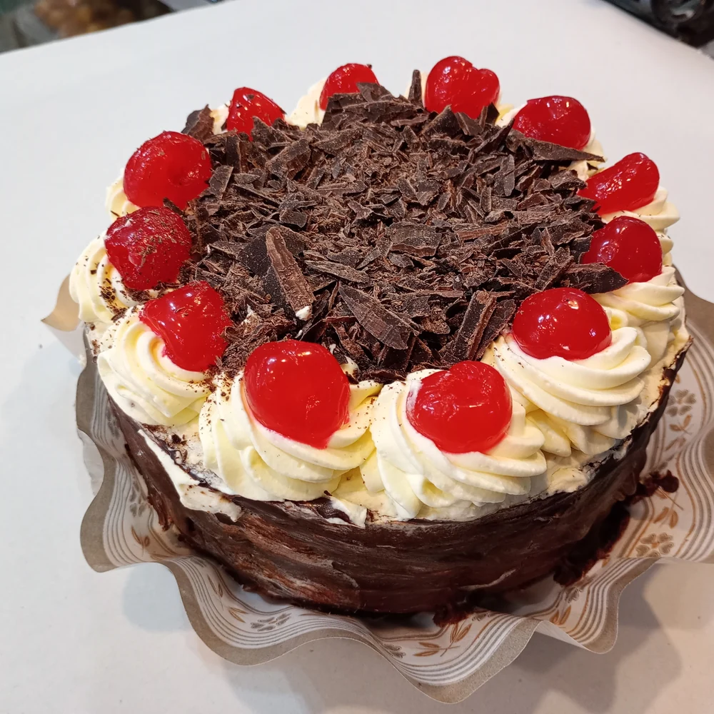 Selva Negra decorada con crema, cerezas y virutas de chocolate